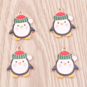 Macro view of four DIY Christmas penguin pendants with winter hats on wood background
