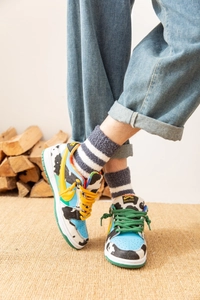 Détail de chaussettes thermiques en polaire rayée avec baskets colorées motif vache