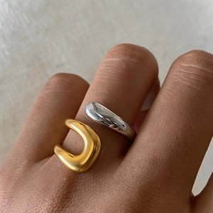 Macro shot of gold and silver organic wave rings on hand with polished mirror finish