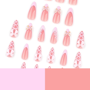 Pink French almond press-on nails featuring 3D white bows, pearls, and ribbon textures