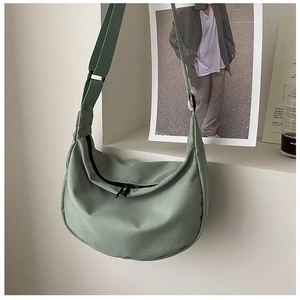 Detailed view of sage green nylon dumpling bag with black zipper and adjustable strap