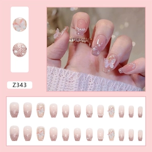 Detail of pink gradient press-on nails with 3D butterflies, pearls, and rhinestones