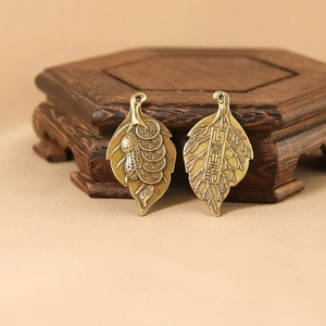 Detailed macro view of two brass leaf pendants with traditional Chinese prosperity symbols