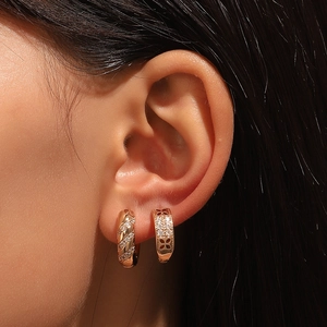 Pair of gold hoop earrings with zircon stones and clover patterns in a macro jewelry view
