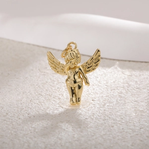 Macro detail of a gold-plated cupid angel pendant with wings on a beige texture