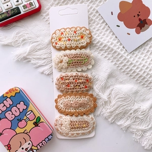 Close-up of five handmade floral knit BB hair clips arranged on a white display card