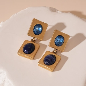 Detail of vintage gold earrings with layered blue resin stones and geometric design