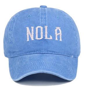 Close-up of embroidered NOLA lettering on washed blue cotton baseball cap detail