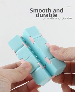 Detail showing hand holding macaron blue and pink infinity cube for stress relief