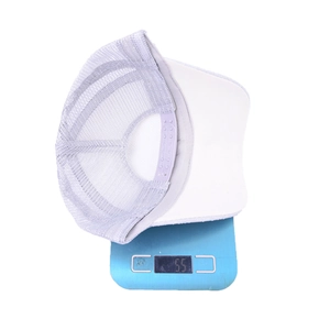 Lightweight white and grey mesh trucker hat being weighed on a scale at 55 grams