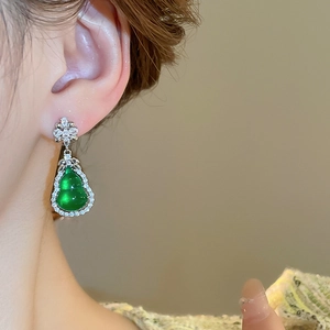 Dettaglio di orecchini a zucca in zircone smeraldo con base in argento su modella
