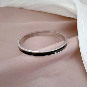 Close-up of polished silver steel bracelet with black enamel inlay on pink silk fabric