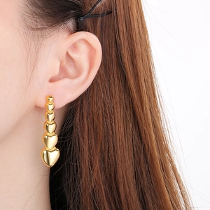 Detail of 18k gold heart-shaped drop earrings showing multiple hearts on a female model