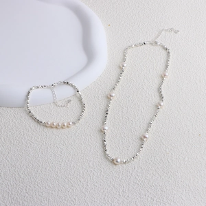 Detailed macro shot of freshwater pearl necklace with geometric silver chain on ceramic