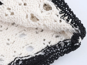 Detail view of the black and white crochet knit pattern on a slim-fit summer dress