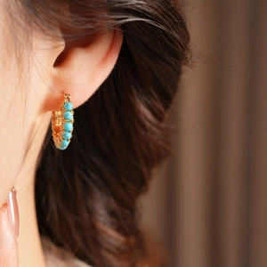 Close-up of 18k gold plated hoop earrings with blue turquoise beads on model