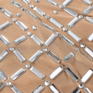 Nahaufnahme von hautfarbenem Netzstoff mit glitzernden Kristallen am Halfterkleid