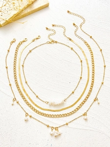 Detail of a four-layer gold necklace set with pearls, snake chain, and heart pendants