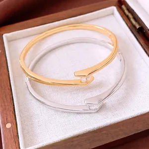 Gold and silver plated bypass bangles with zircon accents shown in a premium jewelry box