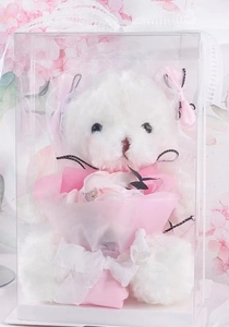 Detail of white plush teddy bear with pink soap flowers in a clear gift box
