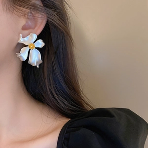 Detailed close-up of a large silver flower earring with a yellow center on a female model