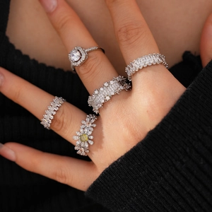 Close-up of stacked silver rings with zircon flower and cushion-cut stones on a hand