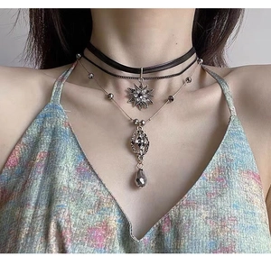 Detail of layered choker with crystal star pendant and drop charms on a model neck