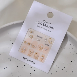 Detail of 3D nail art charms with golden stars, white pearls and geometric patterns