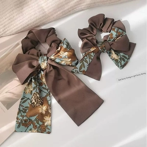 Detailed close-up of retro floral bow hair scrunchies with elegant ribbons and leaf shadows