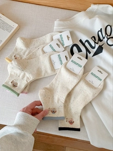 Detail of cute dog embroidery on cream slub yarn ankle socks with colorful ribbed cuffs