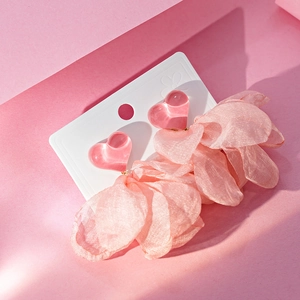Detail of pink heart-shaped earrings with delicate lace fabric petals and soft tassels