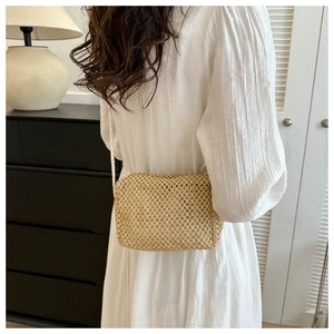 Fashionable straw woven crossbody bag shown on a model in a minimalist room setting
