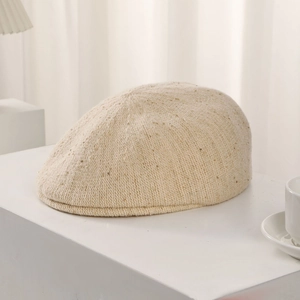 Detailed texture of beige knitted beret with subtle golden sequins and metallic threads