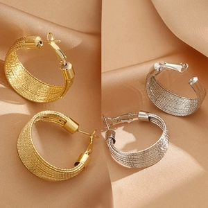 Detail of gold and silver textured earrings with intricate woven metal design