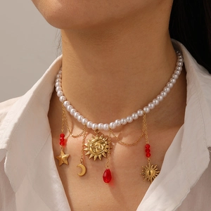 Layered gold chain necklace featuring sun moon star pendants and white pearl choker