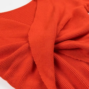 Dettaglio del top in maglia a coste arancione con elegante design a incrocio ritorto