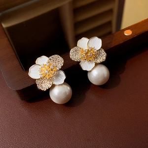 Macro shot of floral pearl earrings with white enamel petals and micro-set cubic zirconia