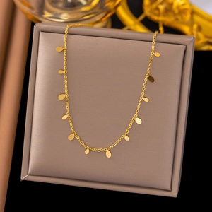 Elegant gold choker necklace with teardrop charms on a grey jewelry display box