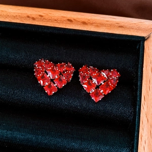 Macro shot of red zircon heart-shaped stud earrings in a premium black velvet jewelry box