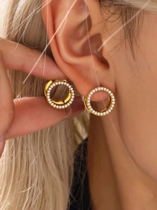 Primer plano de aros dorados con pavé de circonitas blancas en la oreja del modelo