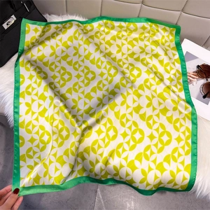 Detailed view of green and yellow silk square scarf with geometric circular patterns