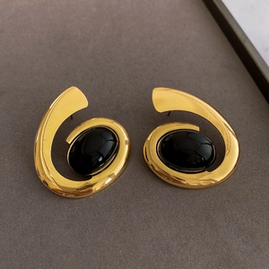 Detailed close-up of golden spiral earrings with black oval resin inlay details