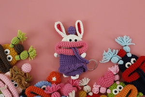 Detail of handmade crochet bunny key case featuring oversized lips and purple dress