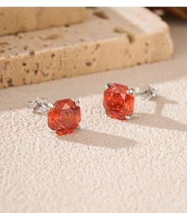 Detailed view of S925 sterling silver studs with faceted orange gemstones on stone