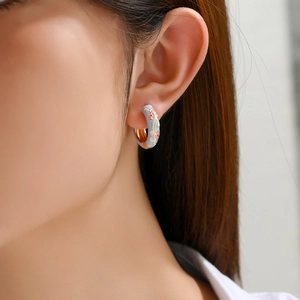 Close-up of vintage hoop earring with light blue enamel and pink flower details on ear