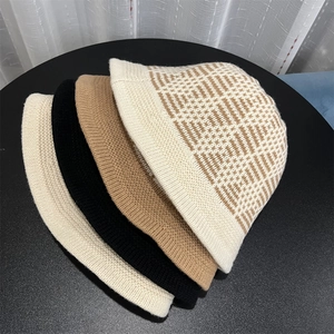 Detail view of colorful knitted bucket hats in cream, black, and beige with jacquard texture