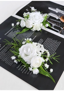 Detail of white artificial rose corsages and pearl wristlet flowers for wedding events