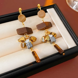 Macro shot of ethnic wooden tassel earrings with tiger eye stone and gold metal accents