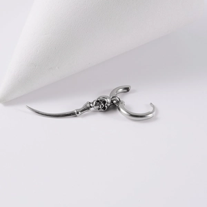 Macro shot of gothic stainless steel earring featuring skull and curved claw pendant