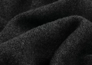 Macro shot of black knitted fabric showing premium fiber texture and soft wool-like folds